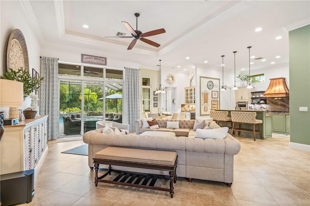 living room featuring a tray ceiling, light tile patterned flooring, recessed lighting, and ornamental molding