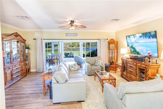 living area featuring a ceiling fan, ornamental molding, light wood-style floors, and a textured ceiling