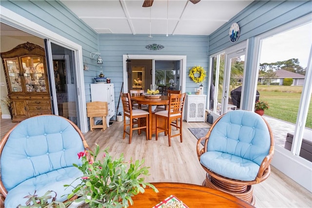 sunroom featuring french doors, a ceiling fan, outdoor dining area, and wood finished floors