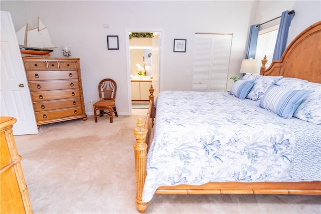 bedroom featuring a closet, light colored carpet, and ensuite bath