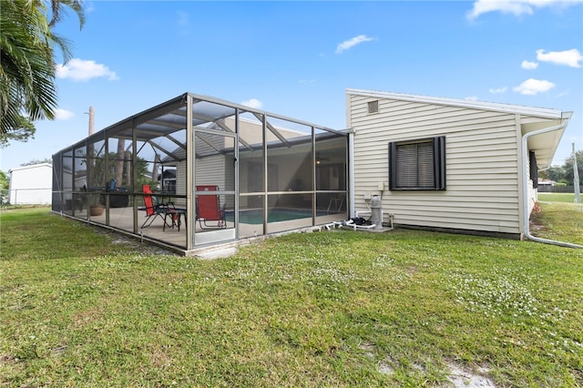 rear view of house featuring a lawn, glass enclosure, and a patio