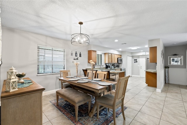 dining space with a textured ceiling, an inviting chandelier, and light tile patterned flooring