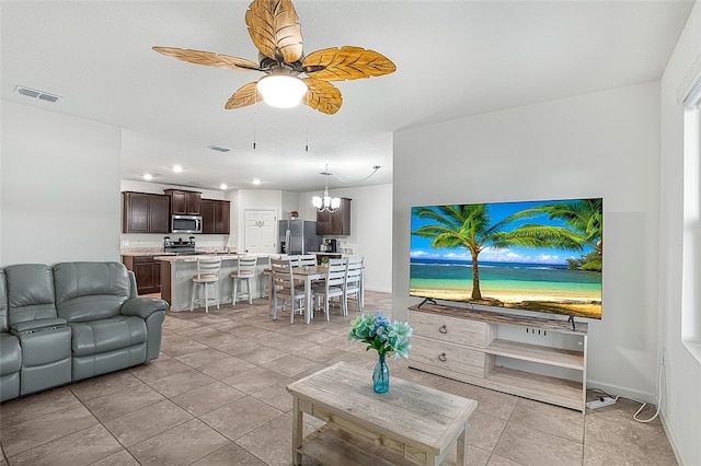 tiled living room featuring ceiling fan with notable chandelier