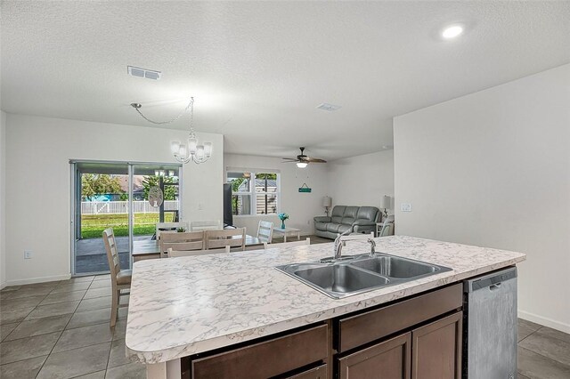 kitchen featuring sink, light tile patterned floors, dishwasher, hanging light fixtures, and an island with sink