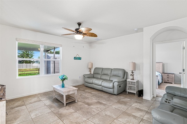 living room featuring a textured ceiling, ceiling fan, and light tile patterned flooring