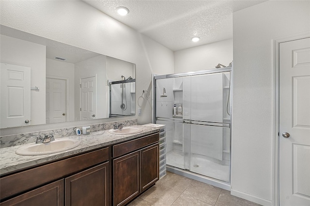 bathroom featuring a shower with door, vanity, tile patterned floors, and a textured ceiling