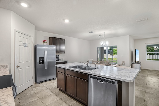 kitchen featuring appliances with stainless steel finishes, an island with sink, sink, dark brown cabinetry, and an inviting chandelier