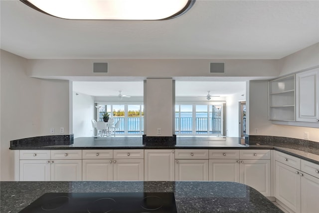 kitchen with white cabinetry, black electric cooktop, ceiling fan, and dark stone countertops