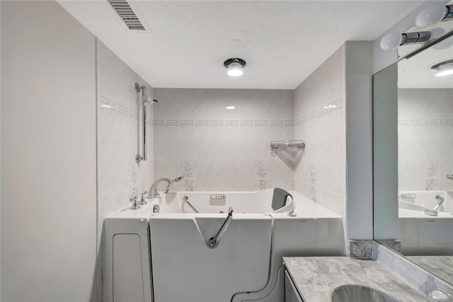 bathroom featuring tile walls, vanity, and a bathing tub