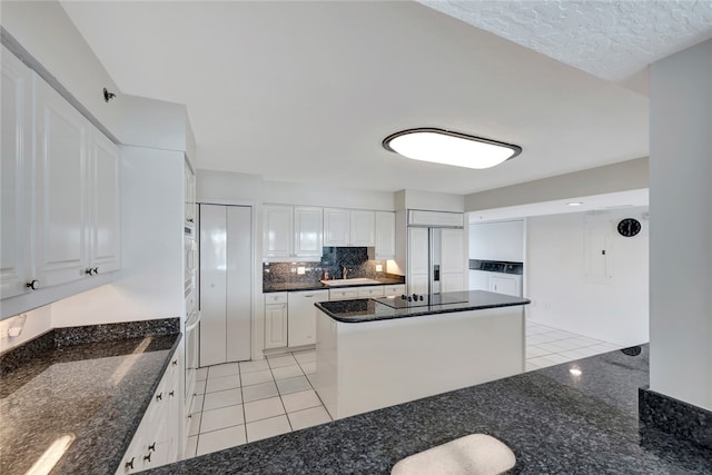 kitchen featuring white cabinetry, dark stone counters, a kitchen island, and paneled fridge