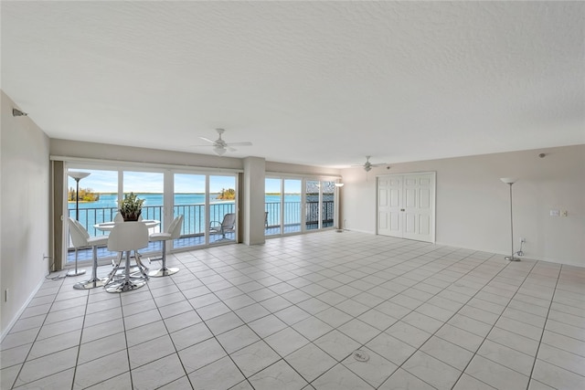 tiled spare room featuring a water view, a textured ceiling, and ceiling fan