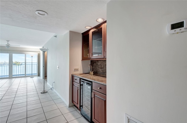 kitchen with sink, a water view, tasteful backsplash, light tile patterned floors, and beverage cooler