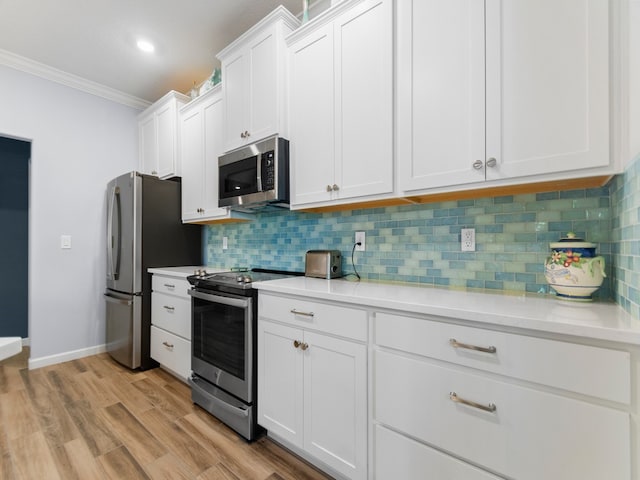 kitchen with stainless steel appliances, white cabinets, tasteful backsplash, crown molding, and light wood-type flooring