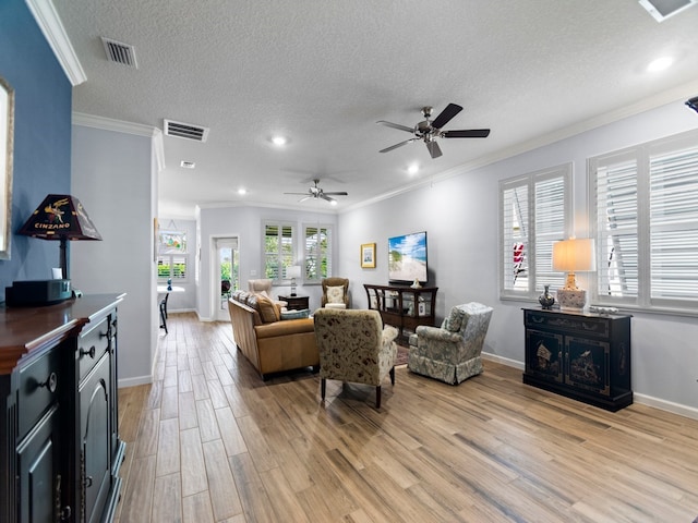 living room featuring light hardwood / wood-style floors, ceiling fan, a textured ceiling, and ornamental molding