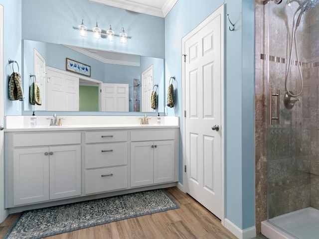 bathroom featuring wood-type flooring, vanity, a shower with door, and crown molding