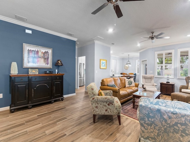 living room featuring ornamental molding, light wood-type flooring, a textured ceiling, and ceiling fan