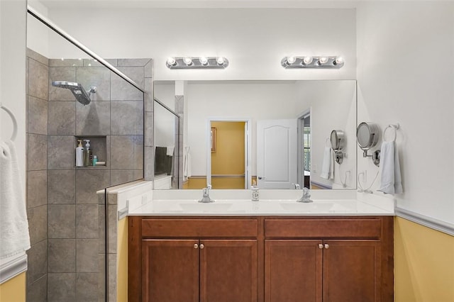 bathroom with a tile shower and vanity