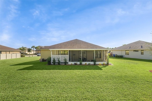 rear view of house with a sunroom and a lawn