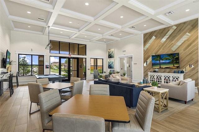 dining room with french doors, coffered ceiling, wood walls, a towering ceiling, and beam ceiling