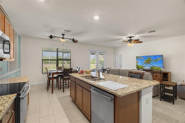 kitchen with ceiling fan, an island with sink, appliances with stainless steel finishes, and sink