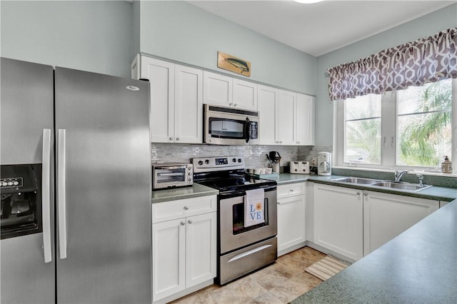 kitchen featuring stainless steel appliances, tasteful backsplash, a sink, and white cabinetry