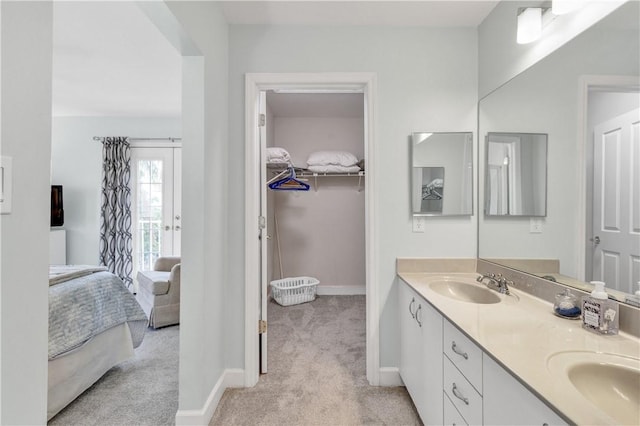 ensuite bathroom featuring double vanity, baseboards, a sink, and ensuite bathroom