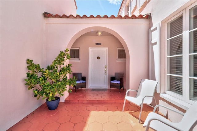 doorway to property with a tiled roof, a patio, and stucco siding