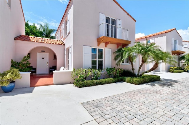 mediterranean / spanish home with a tiled roof, a balcony, and stucco siding