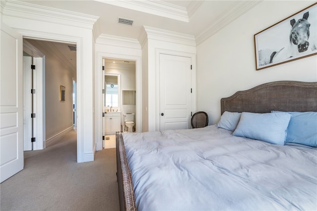 bedroom featuring carpet floors, ensuite bath, and crown molding