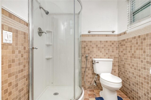 1751 5th Ct, Vero Beach, FL 32960 - bathroom featuring tile walls, a shower stall, toilet, and wainscoting