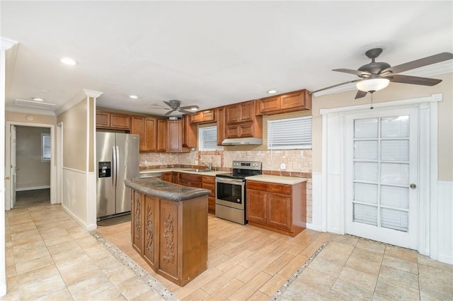 1751 5th Ct, Vero Beach, FL 32960 - kitchen featuring appliances with stainless steel finishes, a ceiling fan, ornamental molding, brown cabinets, and a wainscoted wall