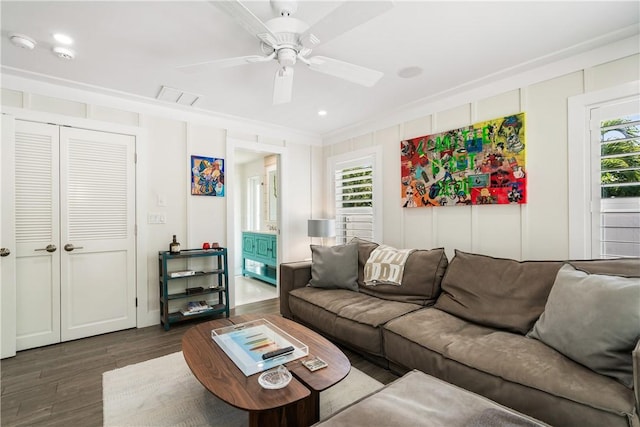 living area featuring dark wood-type flooring, visible vents, ceiling fan, and ornamental molding