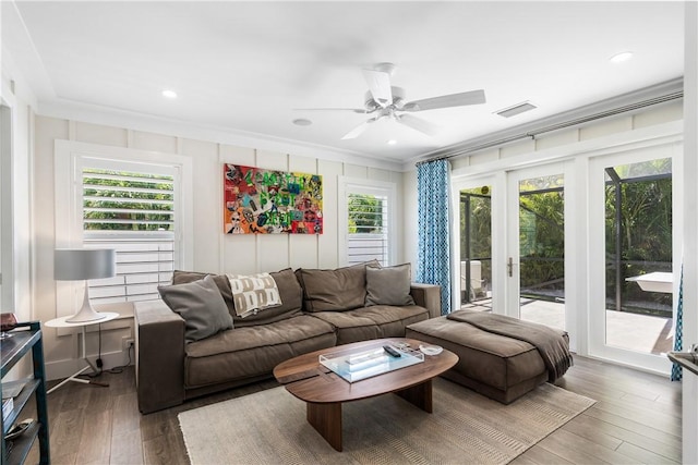 living room with hardwood / wood-style flooring, visible vents, a ceiling fan, french doors, and ornamental molding