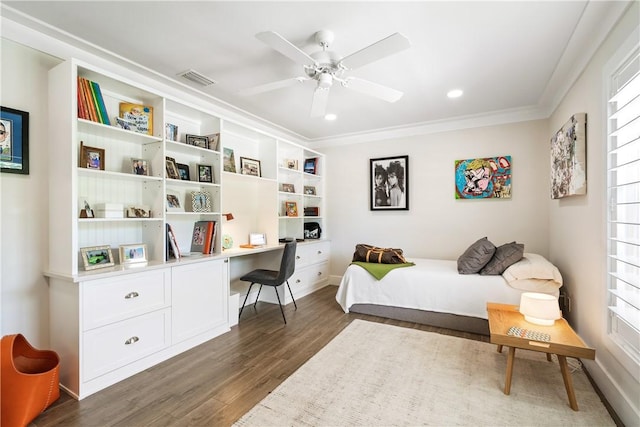 bedroom featuring visible vents, a ceiling fan, built in study area, dark wood-style floors, and ornamental molding