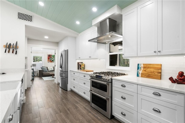 kitchen featuring stainless steel appliances, lofted ceiling, visible vents, backsplash, and wall chimney exhaust hood