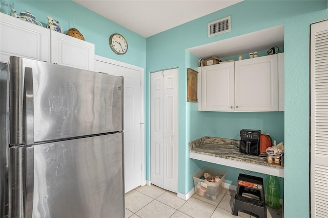 2416 57th Cir Unit 2416, Vero Beach, FL 32966 - kitchen with freestanding refrigerator, light tile patterned flooring, and white cabinetry