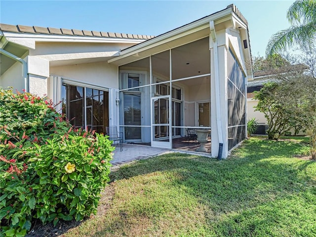 rear view of property with a lawn, a sunroom, and a patio area