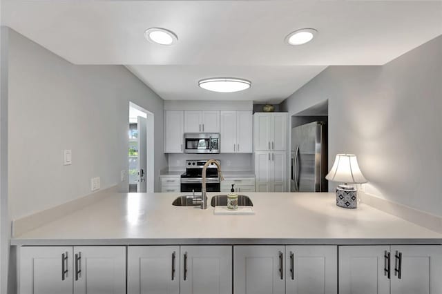 33 Plantation Dr Unit 104, Vero Beach, FL 32966 - kitchen with stainless steel appliances, a peninsula, light countertops, and white cabinetry