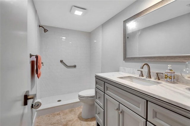 bathroom featuring tiled shower, vanity, toilet, and tile patterned flooring