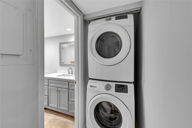 washroom featuring light tile patterned flooring, sink, and stacked washer / dryer