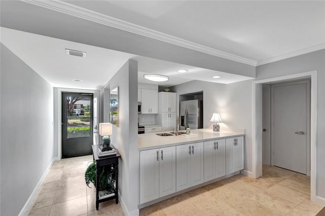 33 Plantation Dr Unit 104, Vero Beach, FL 32966 - kitchen featuring appliances with stainless steel finishes, light countertops, ornamental molding, white cabinets, and a peninsula