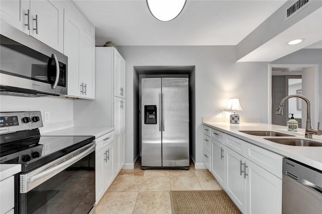 kitchen featuring light tile patterned floors, stainless steel appliances, white cabinetry, and sink