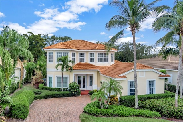 mediterranean / spanish house featuring a tiled roof, french doors, and stucco siding