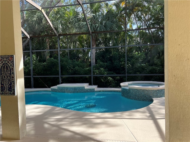 view of pool with glass enclosure, an in ground hot tub, and a patio area