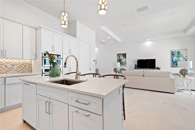 20 Strand Dr, Vero Beach, FL 32963 - kitchen featuring a sink, a raised ceiling, white cabinets, backsplash, and light countertops