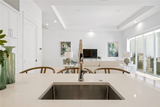 kitchen with white cabinets, a raised ceiling, and sink