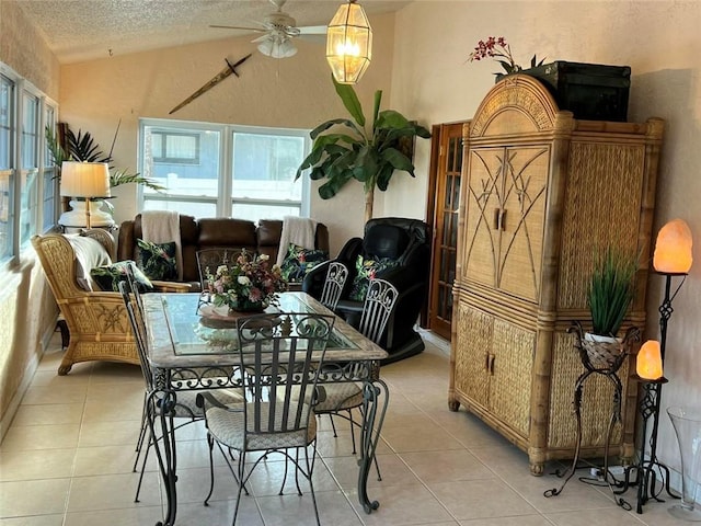 dining area with lofted ceiling, ceiling fan, light tile patterned floors, and a textured ceiling