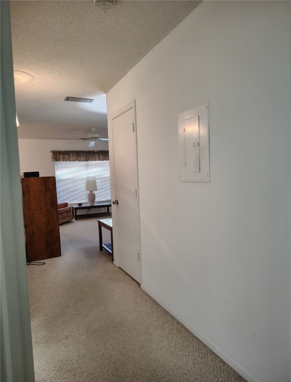 hall with electric panel, carpet floors, and a textured ceiling