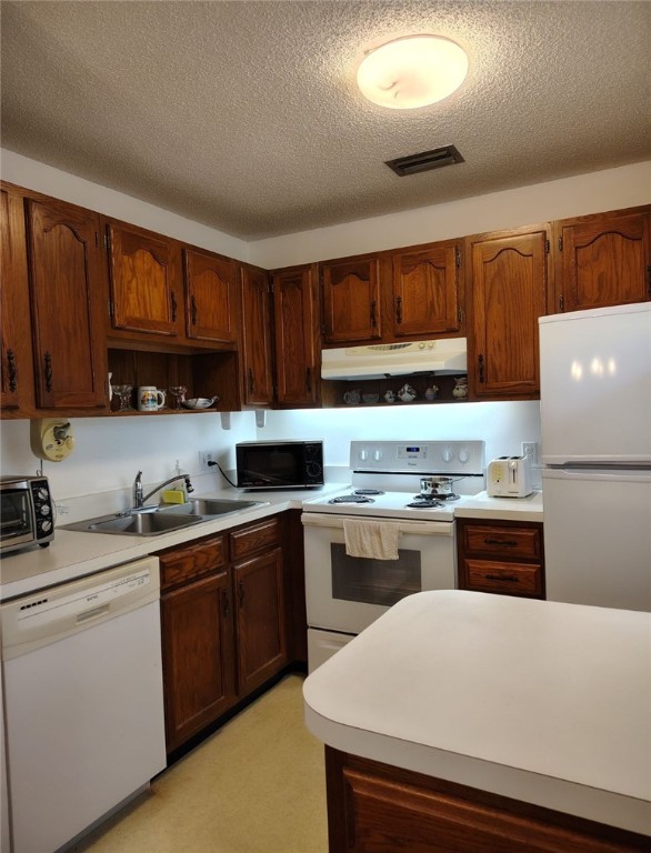 kitchen featuring white appliances, a textured ceiling, and sink