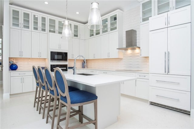 95 Strand Dr, Vero Beach, FL 32963 - kitchen featuring black appliances, wall chimney exhaust hood, a kitchen bar, decorative backsplash, and light countertops